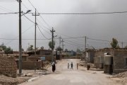 Une des rues principales du camp. Le ciel est obscurci par des fumées noires en provenance des combats autour de Mossoul.
